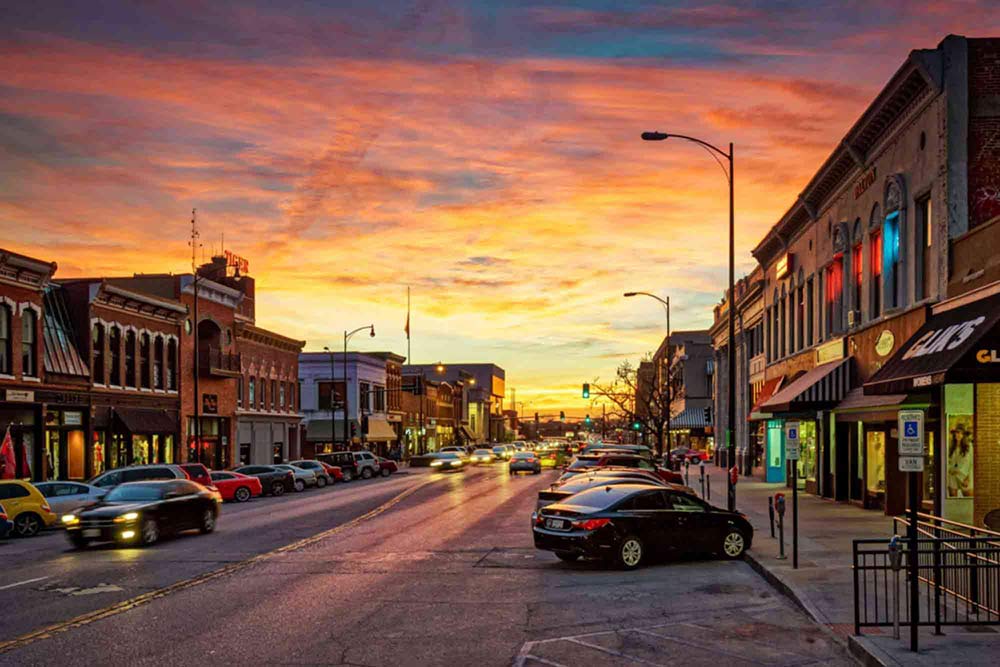 Downtown Columbia, MO, viewing Broadway toward the west, with the sun setting and cars driving.