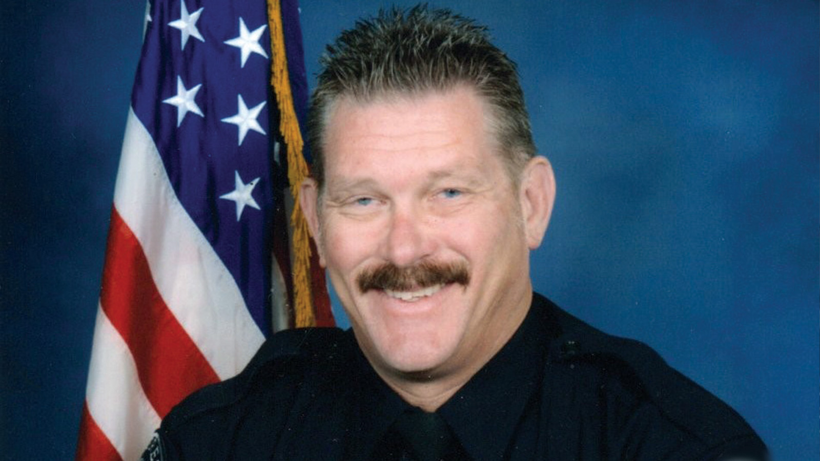 Portrait of Sgt. Michael Wintersole ’15 ’18, with the American flag behind him.