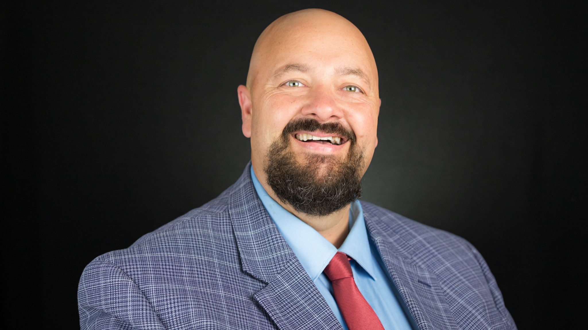 Portrait of Jonathon Moberly, wearing a suit and red tie.