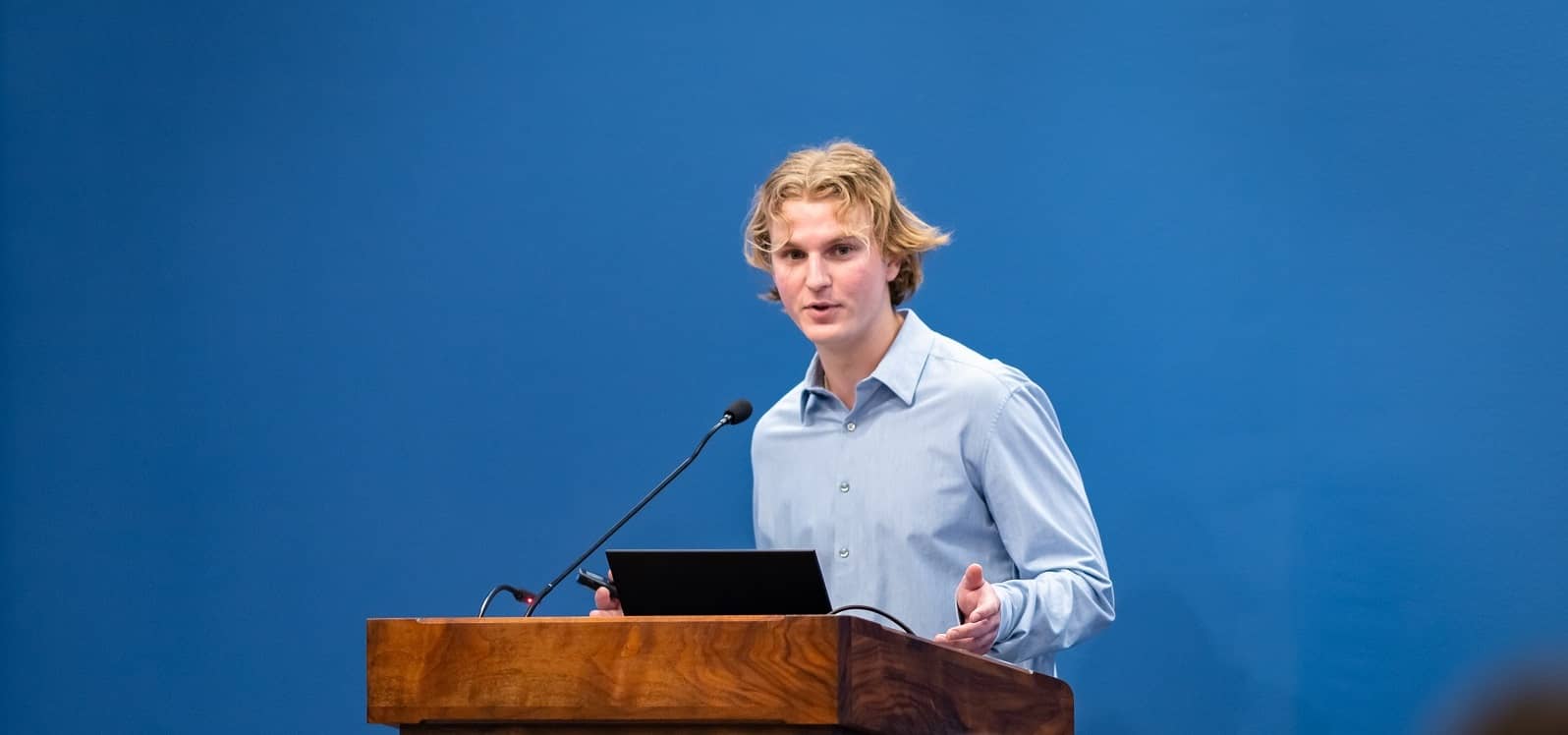 Student presenter standing at the podium, discussing his business proposal.