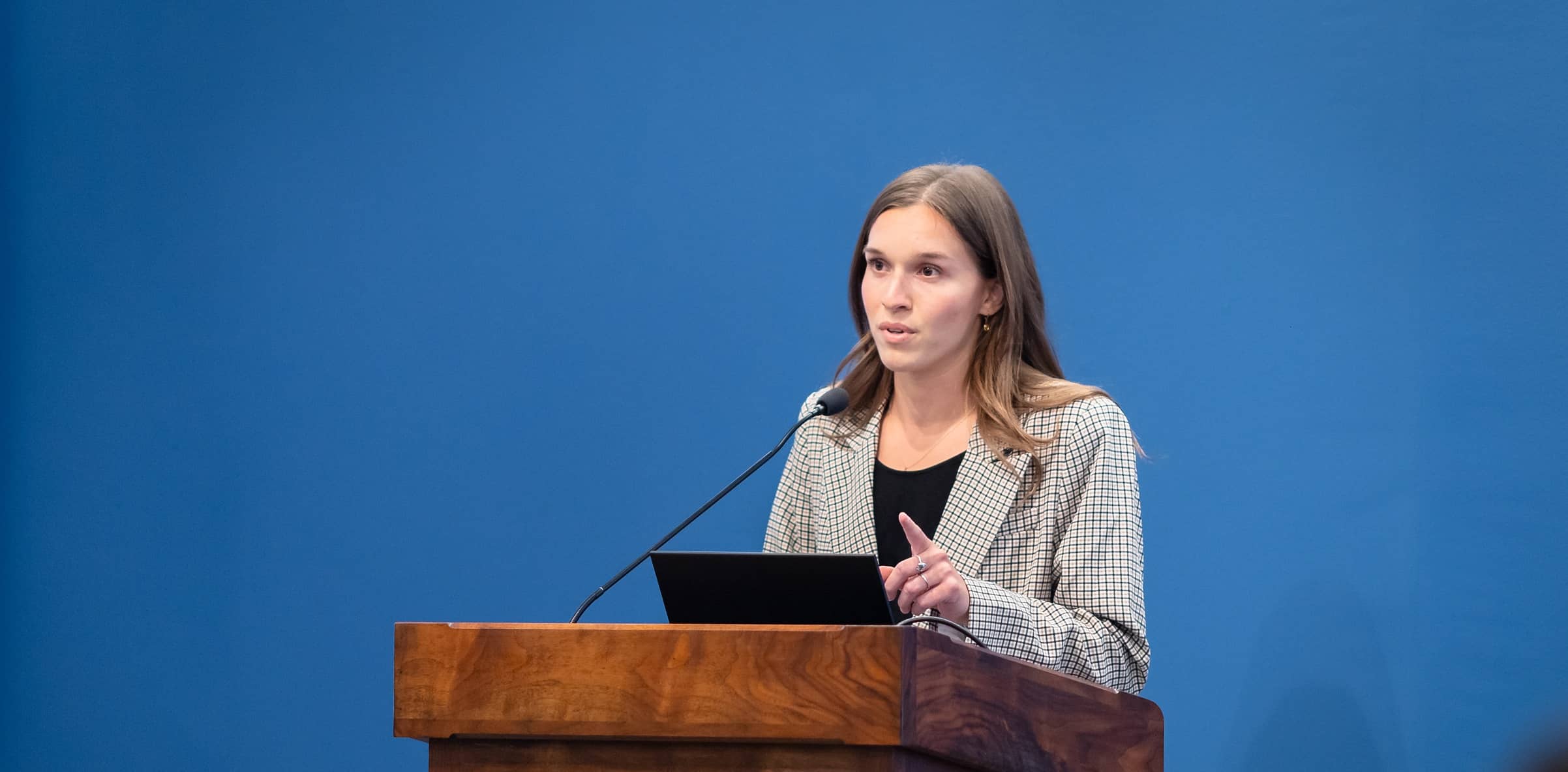 Student Business Competition  Team member discusses her proposal from the podium on stage.