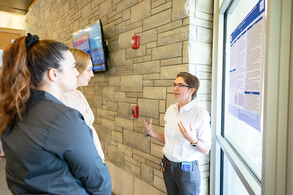 Three students standing in front of a window, having a discussion.