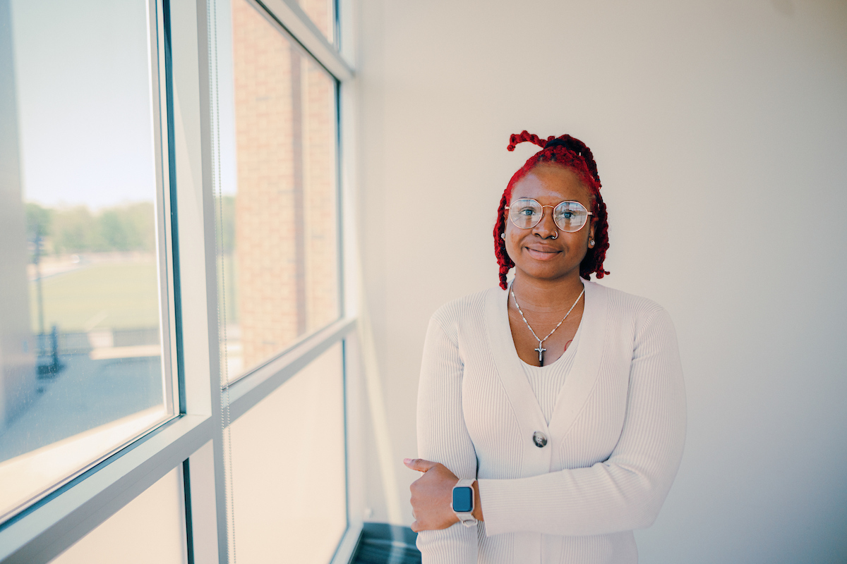 Transfer Work Experience: Woman wearing white suit and glasses standing inside in front of a bank of windows.