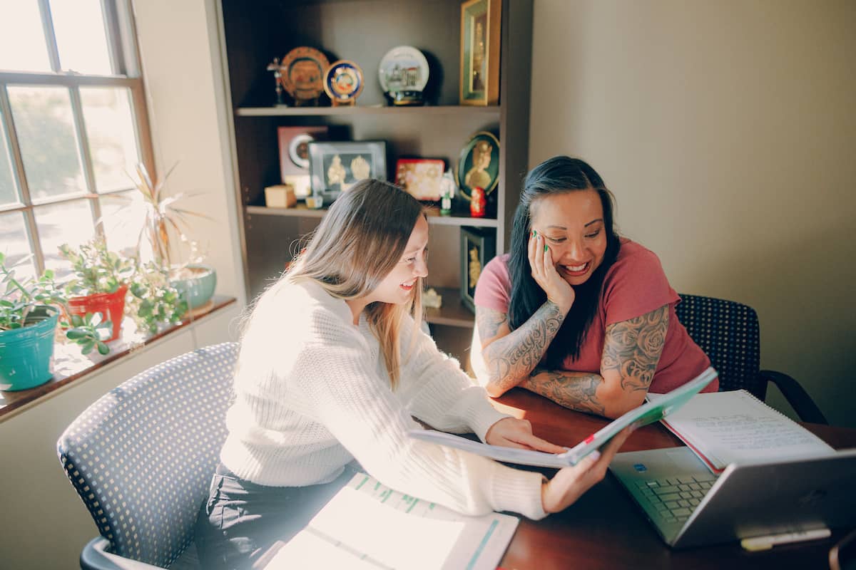 Student sitting at a table, reviewing information on a notepad with her advisor.