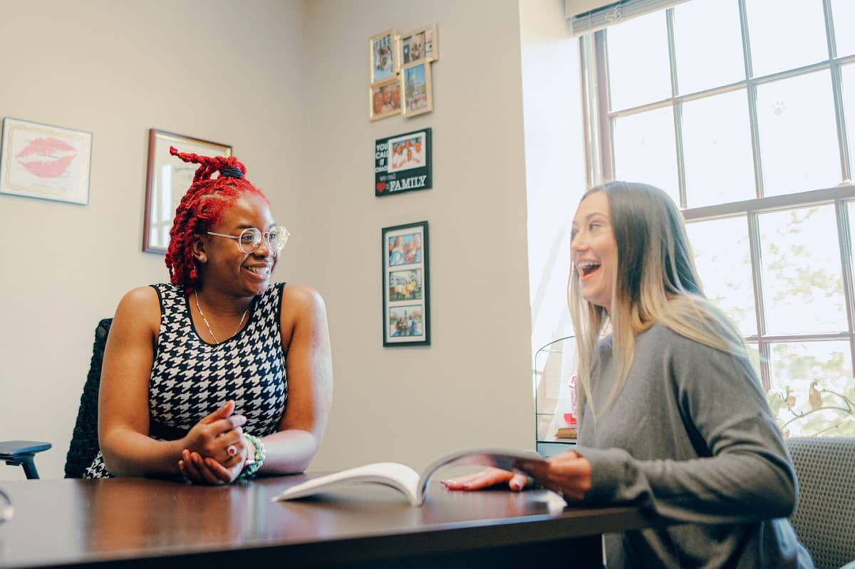 Tuition Benefits: Student discussing tuition options with staff while seated around a table.