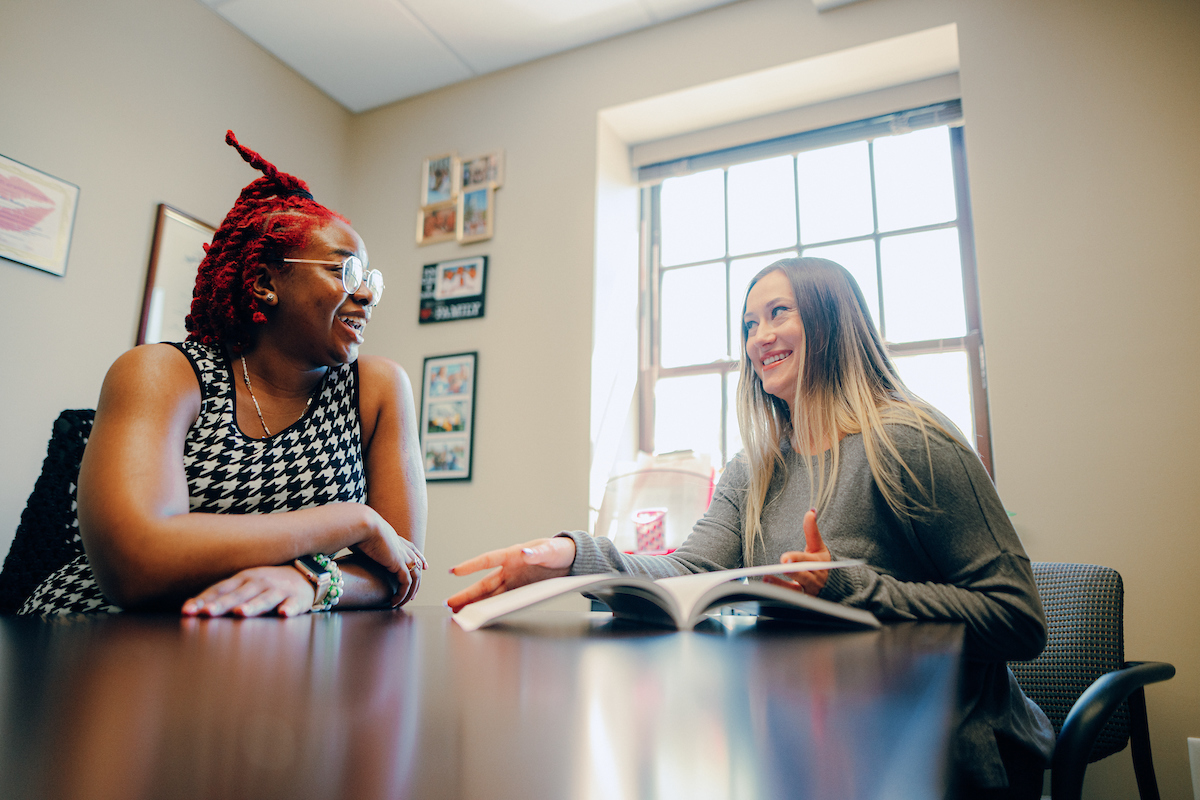 Student sitting at a table, discussing the information in a booklet in front of her with her advisor.