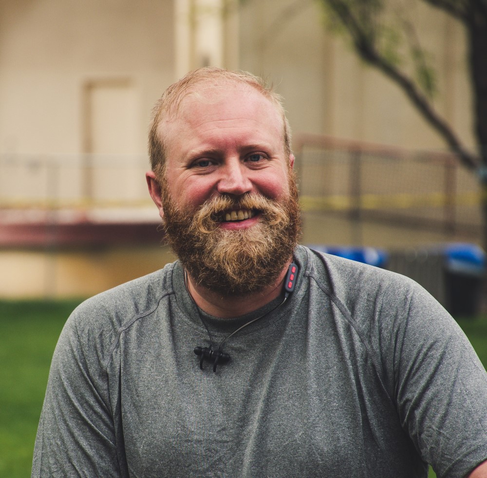 Portrait of a man in beard and a tshirt, smiling at the camera