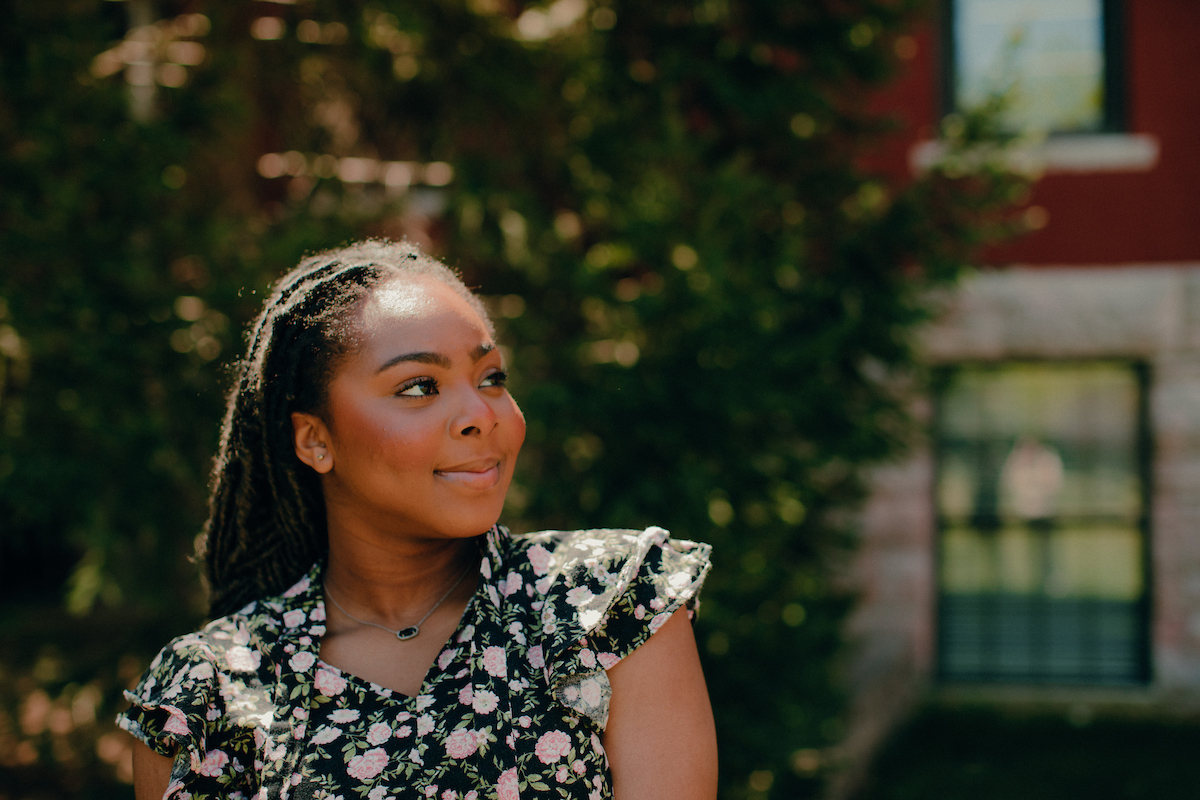 Woman turning to her left to gaze up at the sky and buildings on main campus.