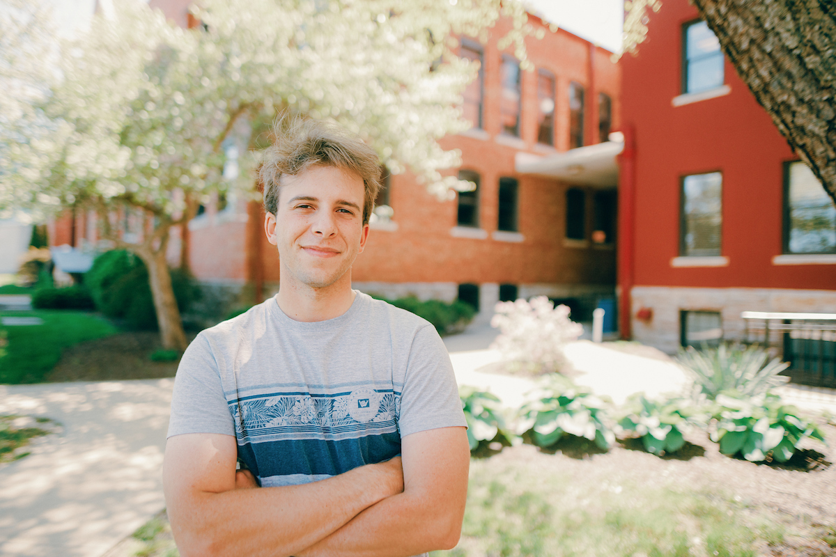 Transfer College Credit: Student standing on the grounds of main campus with arms crossed.