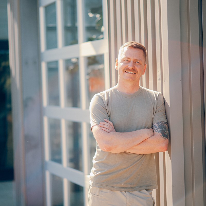 Military: Man with arms crossed wearing military t-shirt.