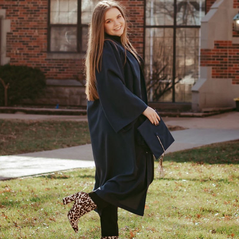 Portrait of Fallon in black cap and gown, looking over her shoulder and smiling